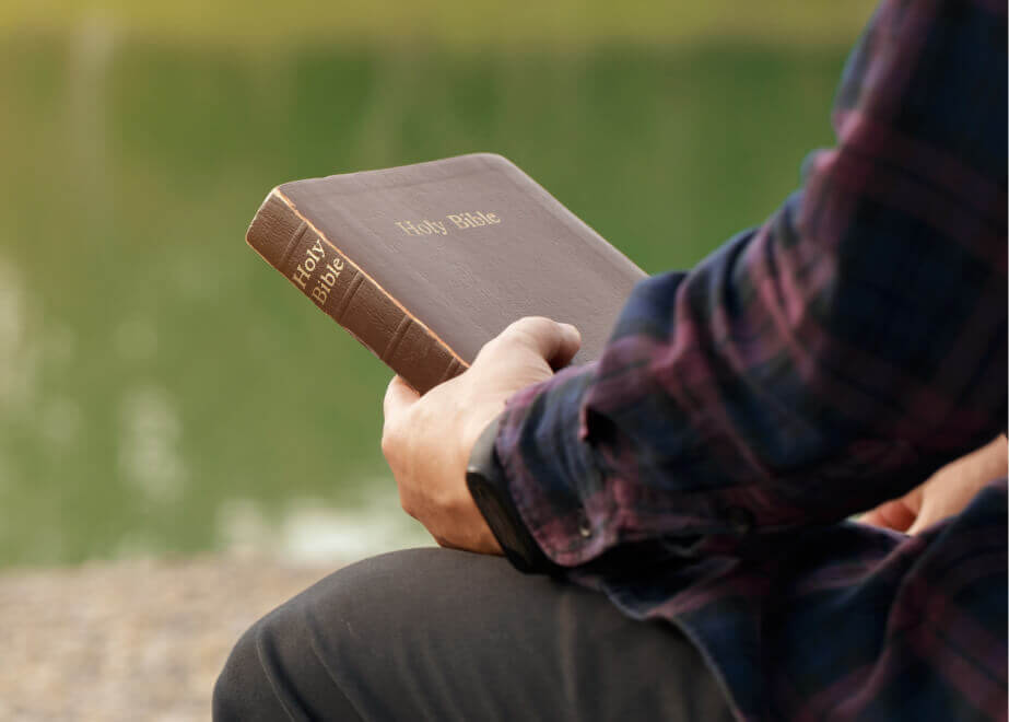 man sitting on a bench holding a book
